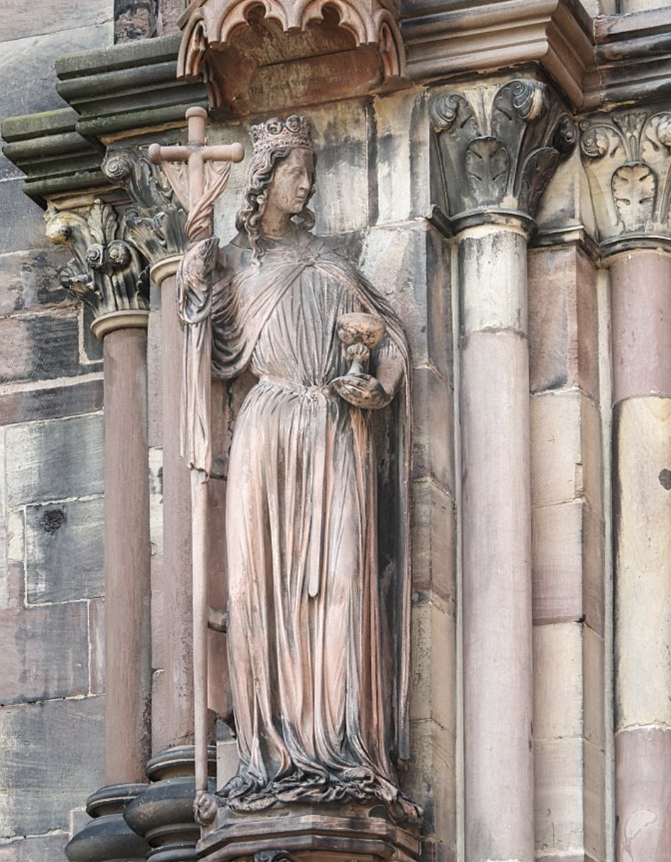 Steinerne Statue der Ecclesia mit Kreuz und Kelch an einer Kirchenfassade